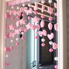 a pink and white heart mobile hanging from the ceiling in front of a door with a window