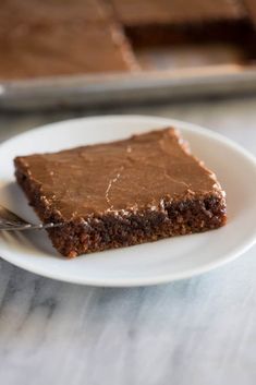 a piece of chocolate cake on a white plate with a fork in front of it