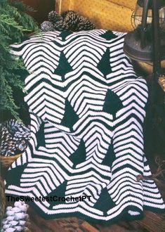 a black and white blanket sitting on top of a wooden floor next to pine cones