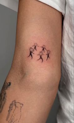 a woman's arm with four small dandelions on the back of it