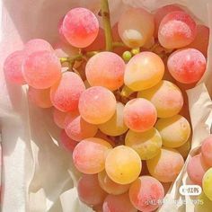 a bunch of grapes sitting on top of a white paper covered in pink and yellow liquid