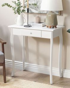 a white table with a lamp and vases on it