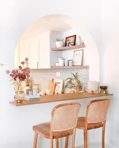 two wooden chairs sitting on top of a counter next to a shelf filled with vases