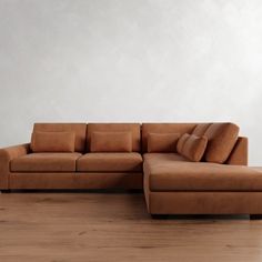 a brown couch sitting on top of a hard wood floor next to a white wall