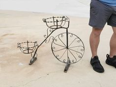 a man standing next to a metal bicycle