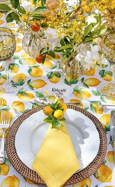 a place setting with yellow napkins and lemons on it, along with silverware