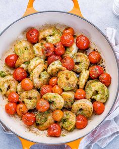 a pan filled with shrimp and tomatoes on top of a white table cloth next to a fork