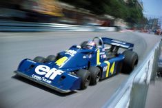 a man driving a blue race car down a street