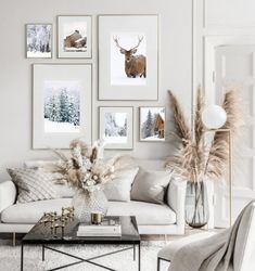 a living room filled with white furniture and pictures on the wall above it's coffee table