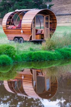 a small wooden house sitting on top of a lush green field next to a lake