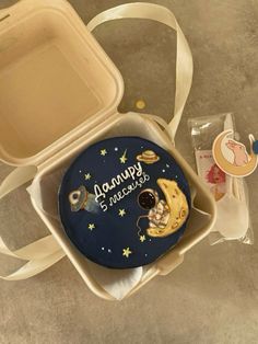 an open lunch box with a cake in the shape of a moon and stars on it