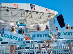 some people are wearing masks and standing on the side of a stage with signs that say coastal