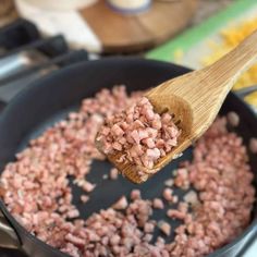 a wooden spoon full of chopped meat in a skillet