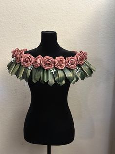 a black mannequin with pink roses and leaves on it's neckline