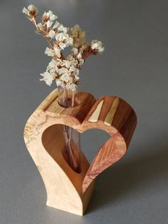 a vase filled with flowers sitting on top of a wooden heart shaped stand next to a plant