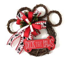 a dog's paw wreath with a red bow and deck the paws sign on it