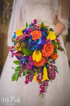 a bride holding a colorful bouquet of flowers