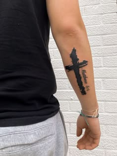 a man with a cross tattoo on his arm