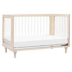 a baby crib that is made out of wood and has white sheets on it