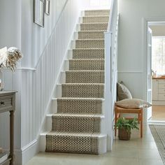 the stairs in this house are lined with woven rugs, and have been painted white