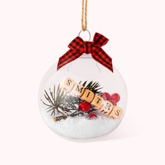 a glass ornament filled with snow, pine cones and other holiday decoration items