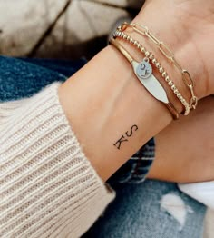 a woman's arm with three different bracelets and a tattoo on the wrist