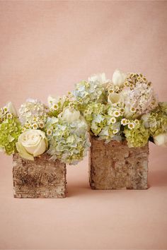 two vases filled with flowers sitting on top of a wooden block next to each other