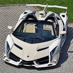 a white and black sports car parked on top of a brick road next to grass