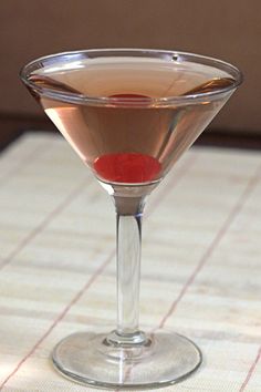 a close up of a martini glass on a table with a red substance in it