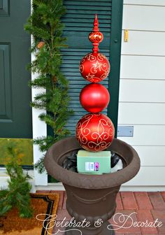 three red ornaments are stacked on top of each other in a potted planter