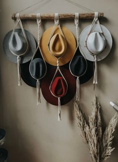 four hats hanging on a wall with string and hooks attached to it, one hat has a tear in the middle