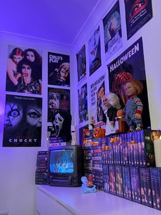 there are many movie posters on the wall behind the tv and in front of it is a small television