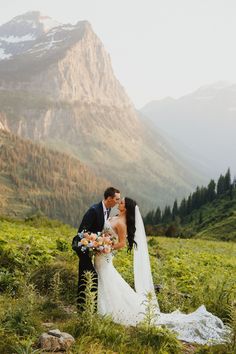 a bride and groom kissing in the mountains