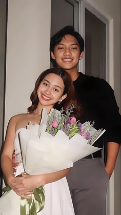 a man and woman standing next to each other with flowers on their bouquets in front of them