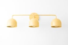 three yellow lights are hanging on the wall in front of a white background and one light is turned off