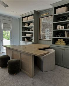 a large wooden table sitting in the middle of a room next to two stools