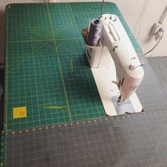 a sewing machine sitting on top of a cutting board next to a ruler and thread