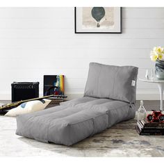 a grey couch sitting on top of a wooden floor next to a vase filled with flowers