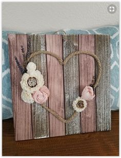 a wooden sign with flowers on it sitting on a table next to a blue pillow