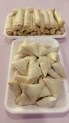 two white trays filled with dumplings on top of a pink tablecloth covered table