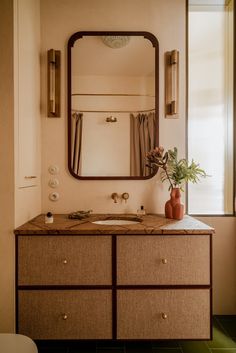 a bathroom with a large mirror above the sink and a vase on top of it