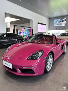 a pink sports car is parked in a showroom