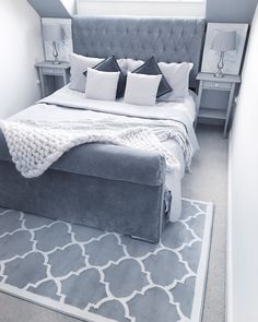 a bedroom with a large bed and gray carpeted flooring in front of a window