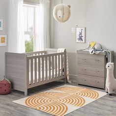 a baby's room with a crib, dresser and rug in the foreground