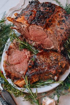 two pieces of meat on a plate with herbs