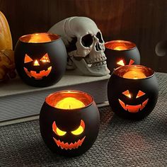 three halloween pumpkins lit up with candles in front of a skull on a table