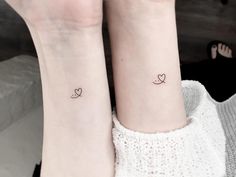 two small tattoos on the wrists of people's legs, one with a heart and another with an arrow