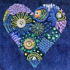 a heart made out of buttons and other items on a blue jean jacket with an embellishment in the shape of a fish