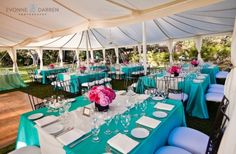 tables and chairs are set up in a tent for an outdoor wedding reception with blue linens and white tablecloths