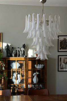 a chandelier hanging over a wooden table in a room with pictures on the wall